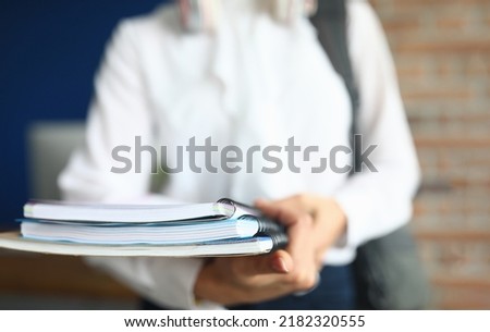 Female student holds folder and notebook in hands for studying