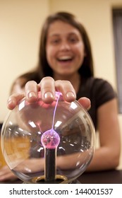 A female student investigates the properties of a plasma ball.