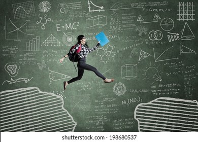 Female student jumping in classroom through gap on the blackboard - Shutterstock ID 198680537