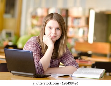  Studentin mit Laptop und Bücher, die in der Oberschulbibliothek arbeiten