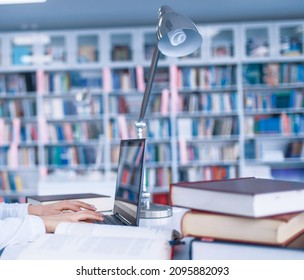 Female student at the laptop in university library. Young woman in reading room, knowledge depository