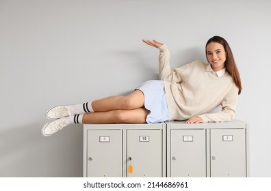 Female student lying on locker against light background - Shutterstock ID 2144686961