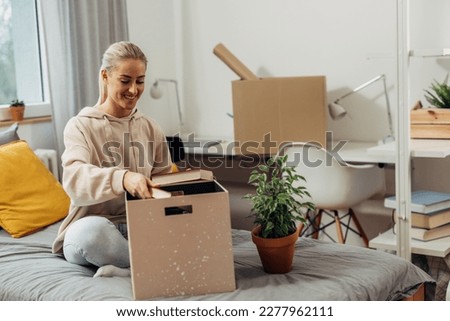 female student moving in dorm room, she is unpacking her staff