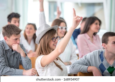 Female Student Raising Hand During Lecture In Classroom