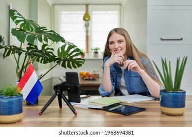 Female student sitting at home studying online, looking at smartphone webcam