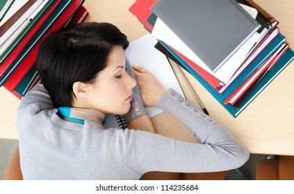 Female Student Sleeping At The Desk With Piles Of Books. Tired Of Training. Top View