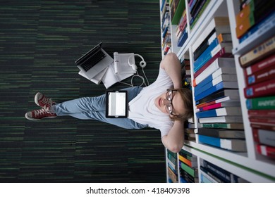 female student study in library using tablet and searching internet while  Listening music and lessons on white headphones