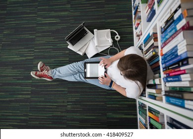 female student study in library using tablet and searching internet while  Listening music and lessons on white headphones - Shutterstock ID 418409527