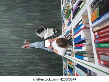 female student study in library using tablet and searching internet while  Listening music and lessons on white headphones - Powered by Shutterstock