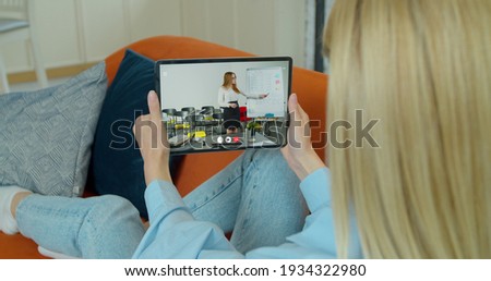 A female student takes an extra lesson distance. Video chat between student and teacher. Over shoulder tabletPC blur screen view.