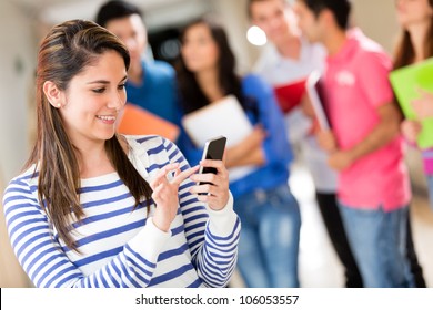 Female Student Texting From Her Cell Phone At The University