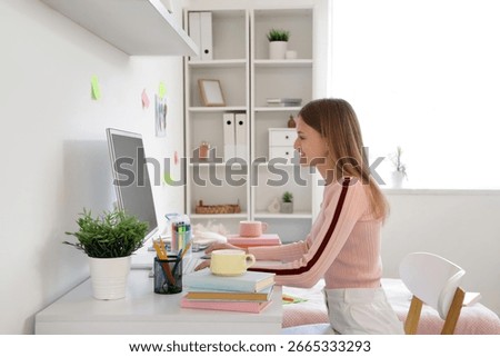 Female student using computer at table in dorm room
