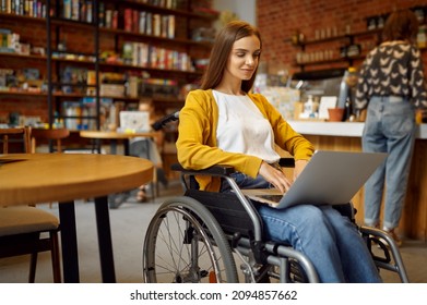 A female student in wheelchair using laptop at university cafe - Powered by Shutterstock