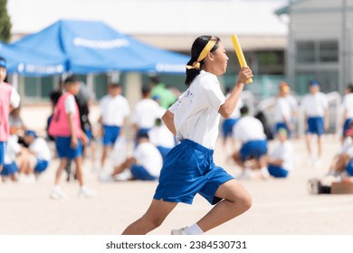 Female students running in relay at junior high school sports festival - Powered by Shutterstock