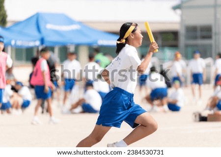 Female students running in relay at junior high school sports festival