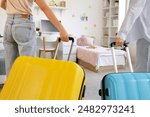 Female students with suitcases in dorm room on moving day, back view