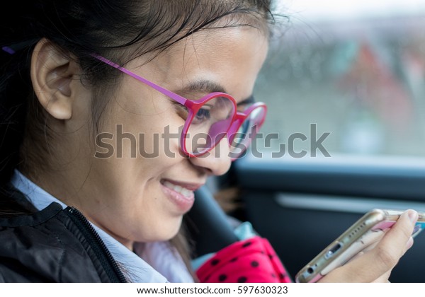 Female students wear glasses\
good play mobile in the car on the road as traffic jams in the\
morning.