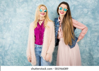 Female stylish friends having fun together on the blue wall background