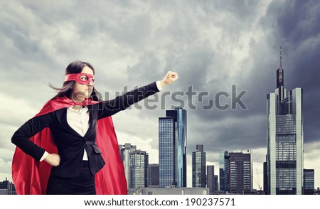 Female superhero standing in front of a dark city 