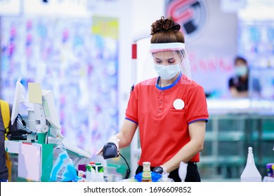 female supermarket cashier in medical protective mask and face shield working at supermarket. covid-19 spreading outbreak  