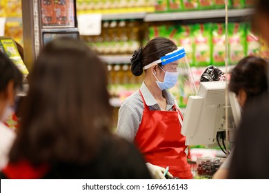 Kasse für Frauen im Supermarkt in medizinischer Schutzmaske und Gesichtsschild, die im Supermarkt arbeiten. Ausbruch der Covid-19-Ausbreitung  
