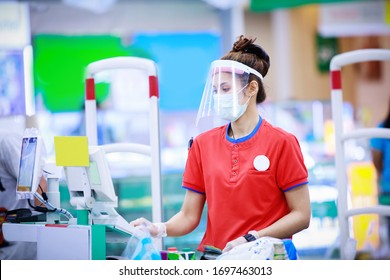 Female Supermarket Cashier In Medical Protective Mask And Face Shield Working At Supermarket. Covid-19 Spreading Outbreak  