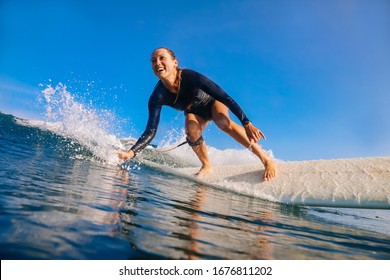 Female Surfer On A Blue Wave At Sunny Day