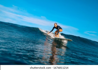 Female Surfer On A Blue Wave At Sunny Day