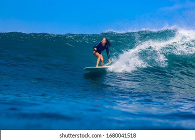 Female Surfer On A Blue Wave At Sunny Day