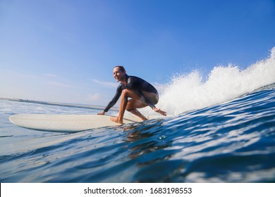 Female surfer on a blue wave at sunny day - Powered by Shutterstock