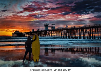 A female surfer is silhouetted as she admires a colorful sunset at Oceanside, California, USA. - Powered by Shutterstock