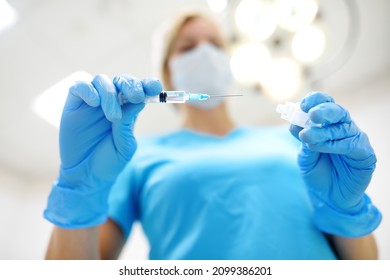 The female surgeon is dialing medicine into a syringe. Doctor is preparing to give an injection to the patient in operation room. Medicine and healthcare. - Powered by Shutterstock