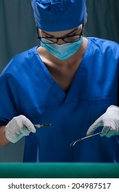 Female Surgeon During Operation With Surgical Scalpel And Scissors