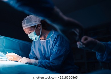 A female surgeon in full surgical attire is seen concentrating on an operation while using various tools, emphasizing her precision, medical skill, and focused determination in the operating room. - Powered by Shutterstock