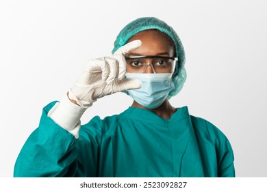 Female surgeon, healthcare worker in green scrubs, mask, and gloves. African American female in medical attire. Female healthcare professional in protective gear. African American feamle surgeon. - Powered by Shutterstock