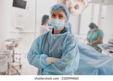 Female surgeon in mask standing in operating room with crossing hands, ready to work on patient - Powered by Shutterstock