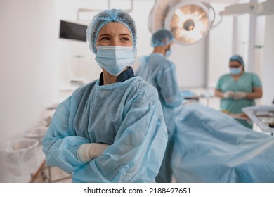 Female Surgeon In Mask Standing In Operating Room With Crossing Hands, Ready To Work On Patient