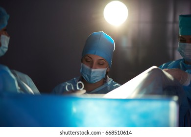 Female surgeon performing surgery with her colleagues team of nurses and doctors at the hospital operating theatre profession occupation job experience skills healthcare medical concept.