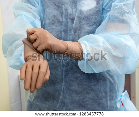 A female surgeon prepares for a surgical operation puts on sterile surgical gloves and kneads his hands