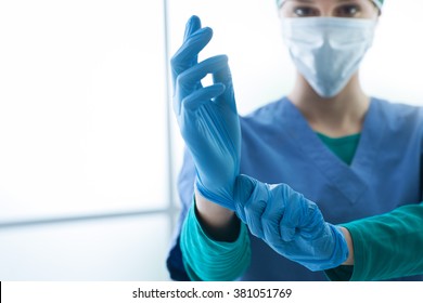 Female surgeon preparing for the surgical operation, she is wearing gloves and looking at camera, healthcare and preparation concept