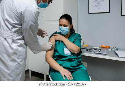 Female surgeon receiving coronavirus vaccine at doctor's office - Powered by Shutterstock