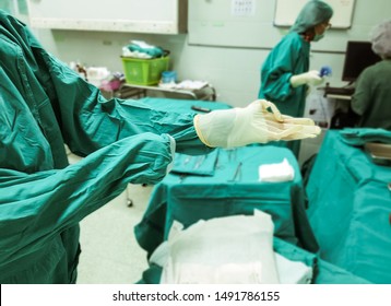 Female surgeon or scrub nurse wearing surgical gloves and gowning with proper technique before stating operation