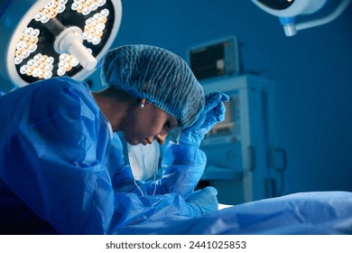 Female surgeon standing in operating room being exhausted and tired - Powered by Shutterstock