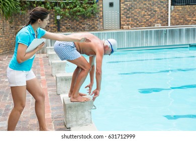 Female swim coach assisting senior man in swimming - Powered by Shutterstock