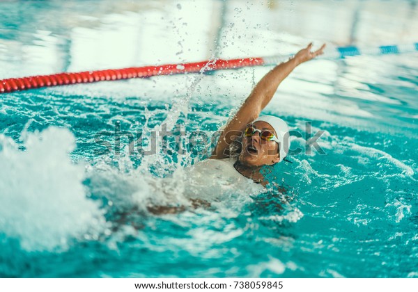 Female swimmer on training in the swimming pool.\
Backstroke swimming\
style