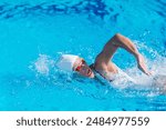 Female swimmer performing front crawl in outdoor pool. Active woman, swimming technique, fitness, water sport, healthy lifestyle