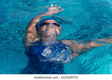 Female swimmer still submerged as she ascends to the surface of pool after flip turn during swim meet race. - Powered by Shutterstock