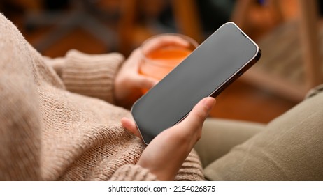 Female Taking A Break In Her Living Room, Sitting On Armchair And Using Cellphone Chatting With Her Friends. Close-up Image