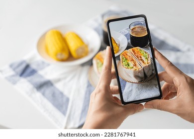 Female taking photo of healthy sandwiches with smart phone to share on social media