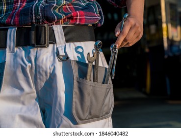 A female taking tools from her pocket, wearing working clothes